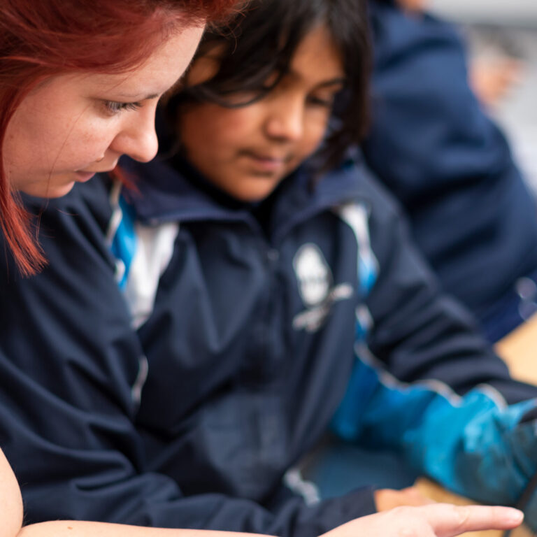 Head of Technology teaching a Devonshire House student on a tablet.